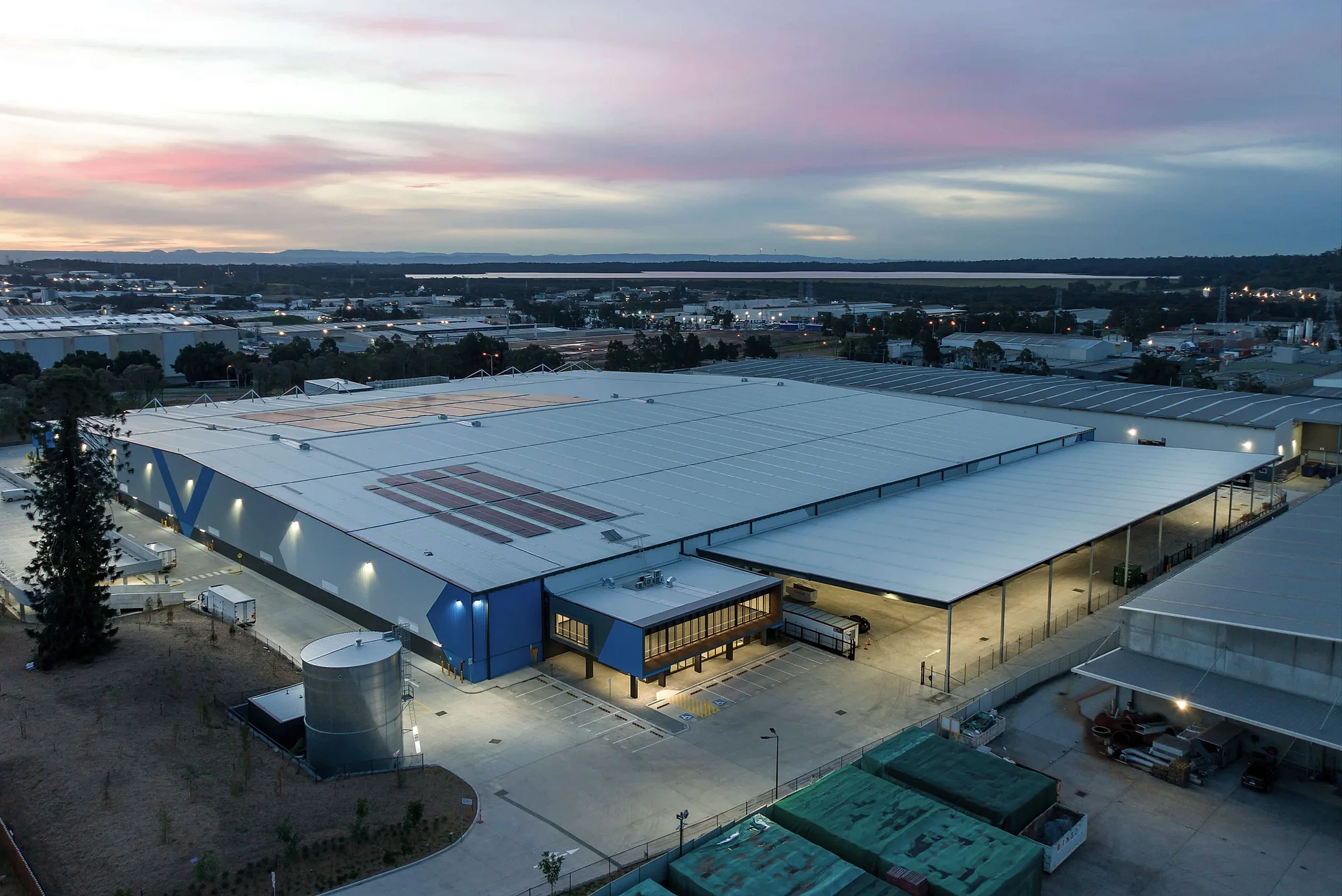 Aerial view of a large commercial warehouse with rooftop solar at dusk