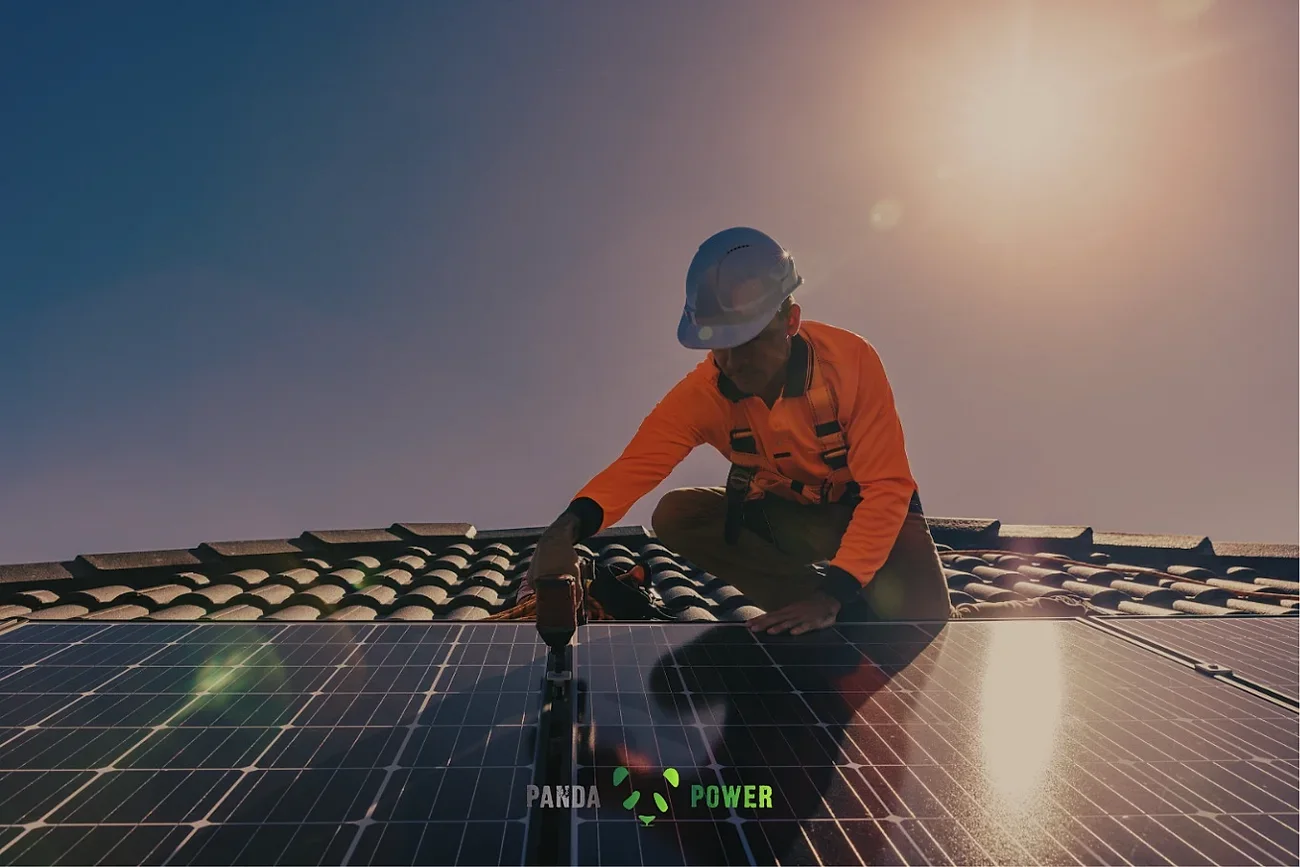 Panda Power installer securing panels on a tiled roof at sunrise