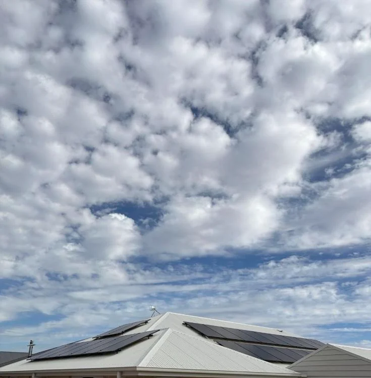 Black solar panels installed under a dramatic sky